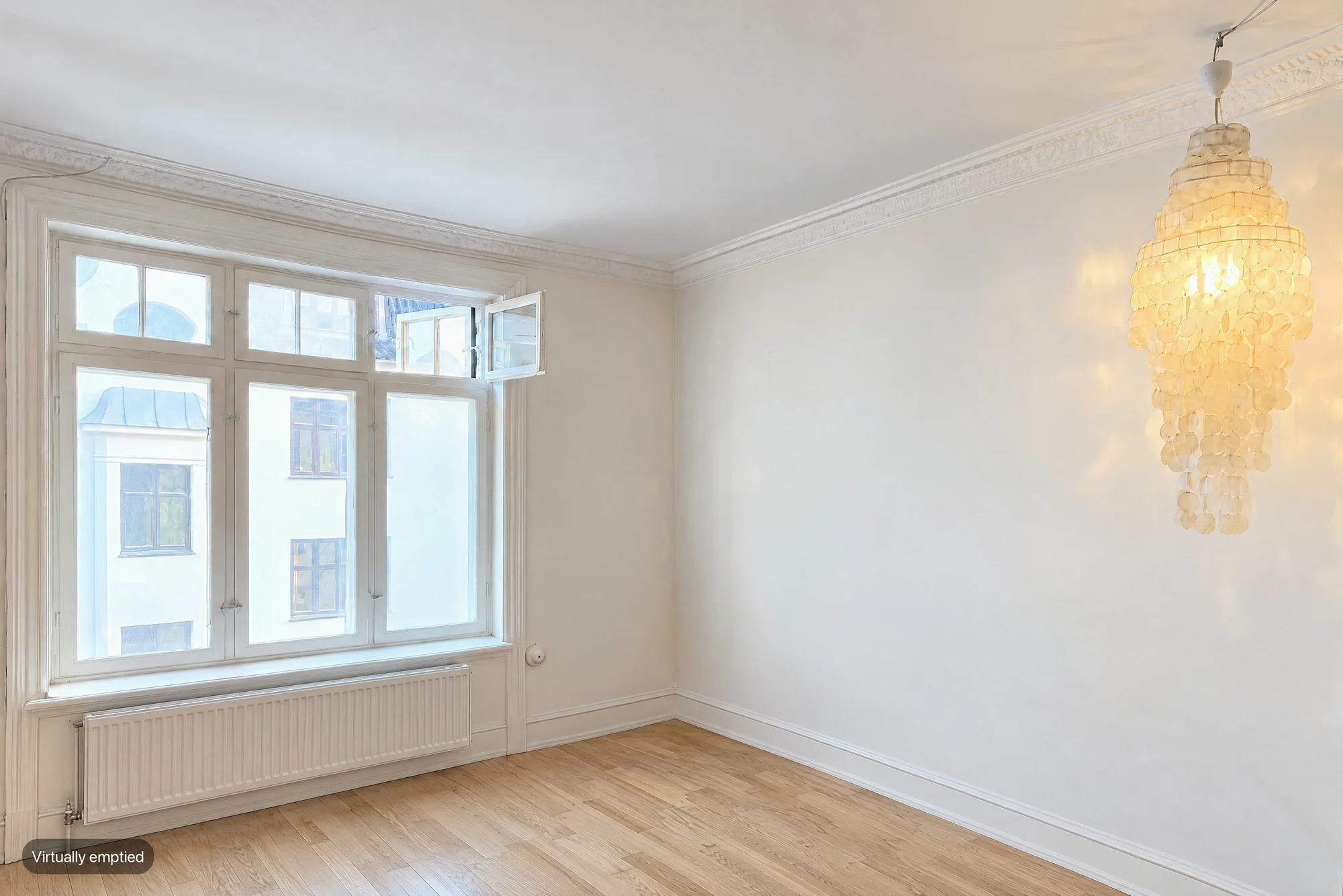The same living room virtually emptied, showing bare walls, a radiator under the window and a wooden floor, labelled Virtually emptied