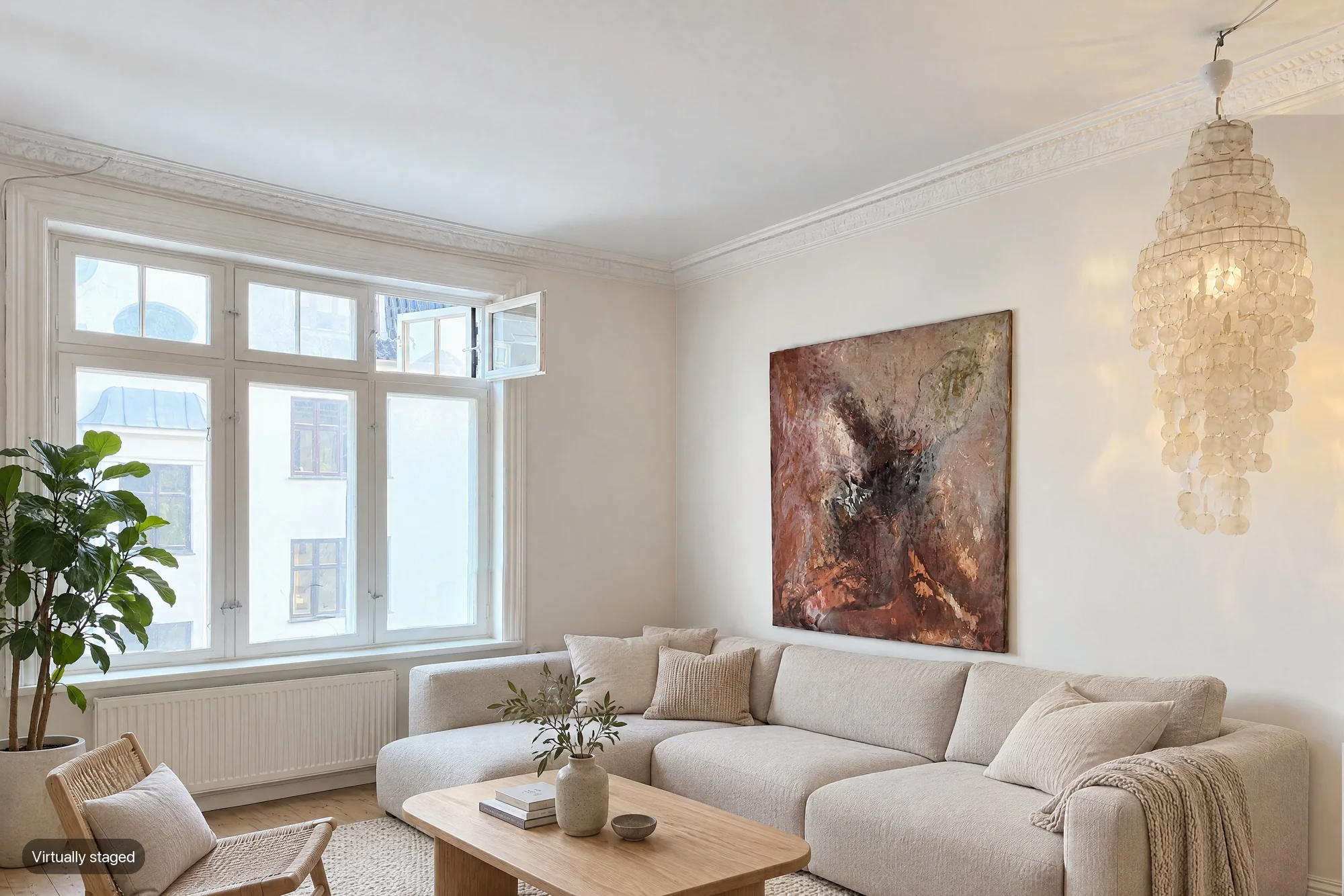 A living room with tall windows and a large abstract painting, virtually staged with a light sofa, wooden coffee table, rattan chair and plant, labelled Virtually staged